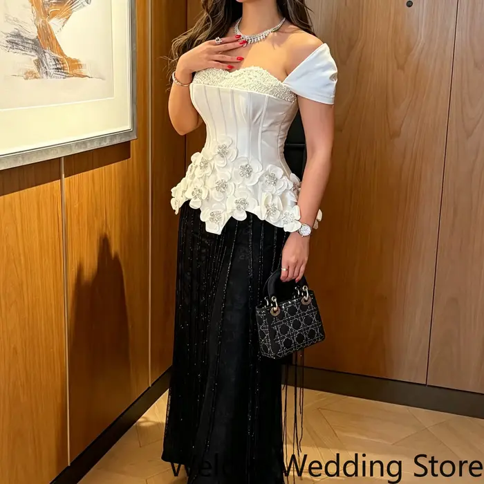 Robe de soirée formelle noire et blanche avec un décolleté épaules dénudées, un corsage structuré or