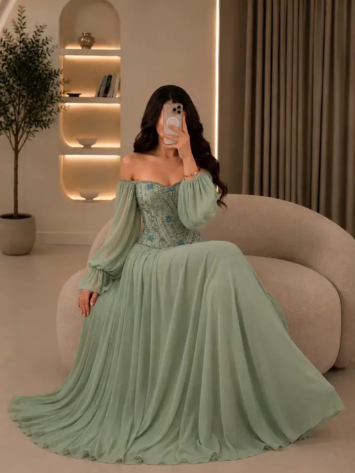 Robe de demoiselle d'honneur pour mariage au jardin à Dubaï, style henné | Robe en mousseline de soie vert sauge, épaules dénudées, manches longues bouffantes, ornée de cristaux bleus cousus main