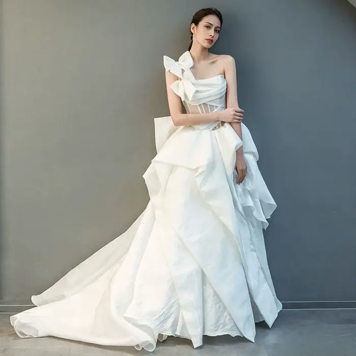 Robe de mariée moderne personnalisée asymétrique en organza coupe trapèze avec grand nœud et volants